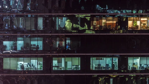 Oficina rascacielos exterior durante la tarde con luces interiores encendidas y personas que trabajan dentro de la noche timelapse —  Fotos de Stock