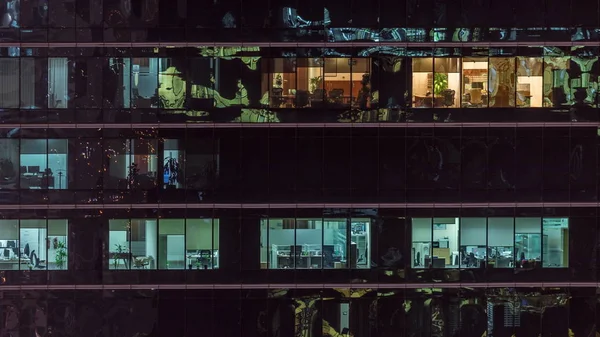 Oficina rascacielos exterior durante la tarde con luces interiores encendidas y personas que trabajan dentro de la noche timelapse —  Fotos de Stock