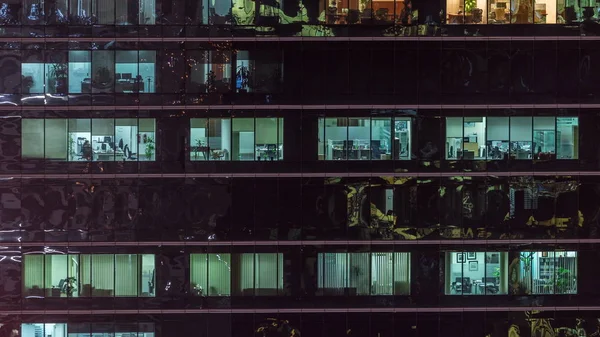 Oficina rascacielos exterior durante la tarde con luces interiores encendidas y personas que trabajan dentro de la noche timelapse —  Fotos de Stock