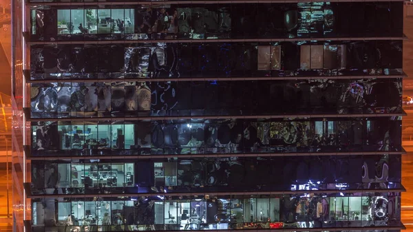 Внешний вид офисного небоскреба поздним вечером с включенным внутренним освещением и людьми, работающими в ночное время — стоковое фото