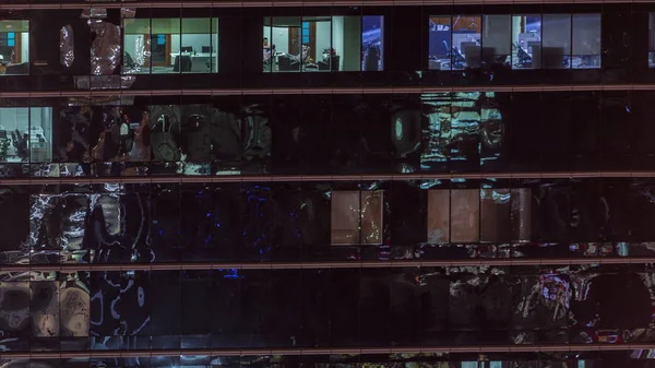 Oficina rascacielos exterior durante la tarde con luces interiores encendidas y personas que trabajan dentro de la noche timelapse —  Fotos de Stock