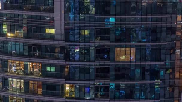 Filas de ventanas brillantes con gente en el edificio de apartamentos por la noche . — Vídeos de Stock