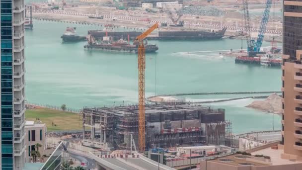 Légi kilátás egy felhőkarcoló építés alatt álló hatalmas daruk timelapse Dubai kikötő. — Stock videók