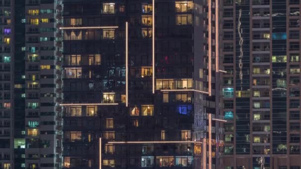 Rader av glödande fönster med människor i lägenhetsbyggnad på natten. — Stockvideo
