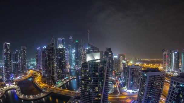 Vista aérea de los rascacielos residenciales y de oficinas de Dubai Marina con timelapse nocturno frente al mar — Vídeos de Stock