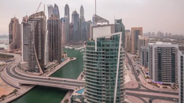 Vista aérea de los rascacielos residenciales y de oficinas de Dubai Marina con timelapse de día a noche frente al mar — Vídeos de Stock