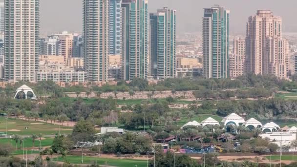 Pole golfowe w Dubaju z pejzażem miejskim dzielnic Gereens i tecom w tle antenowy timelapse — Wideo stockowe