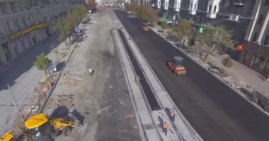 Asfalt, kaldırım yolunda makine ve titreşim silindiri yayıyor.