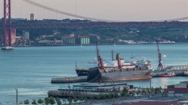 Skyline nad portem handlowym w Lizbonie dzień do nocy timelapse, 25 kwietnia Bridge, kontenery na molo z dźwigami towarowymi — Wideo stockowe