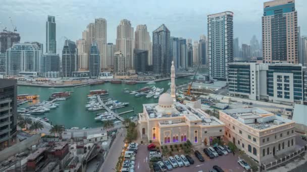 Yates en Dubai Marina flanqueado por la mezquita Al Rahim y torres residenciales y rascacielos antena día a noche timelapse . — Vídeo de stock