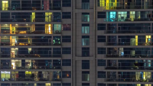Ряды светящихся окон с людьми в многоквартирном доме ночью . — стоковое видео