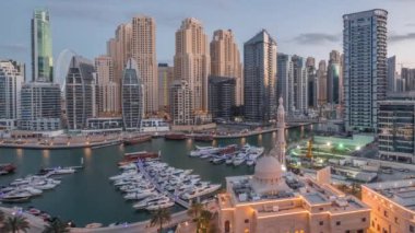 Dubai Marina 'daki yatlar El-Rahim Camii' nin ve konut kulelerinin ve gökdelenlerin yan tarafındaki yatlar gece gündüz gökdelenler.