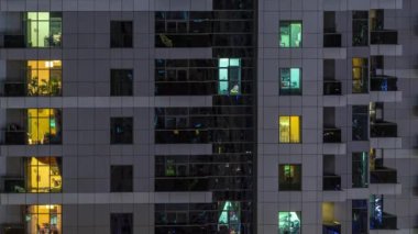 Geceleri apartmanda insanların oturduğu parlak pencereler..