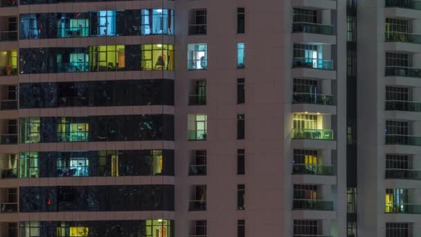 夜にアパートの建物の人々と輝く窓の行. — ストック動画