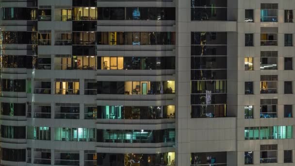 Filas de ventanas brillantes con gente en el edificio de apartamentos por la noche . — Vídeo de stock