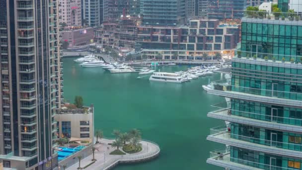 Vista aérea dos arranha-céus residenciais e de escritório da Marina do Dubai com a timelapse do dia à noite à beira-mar — Vídeo de Stock