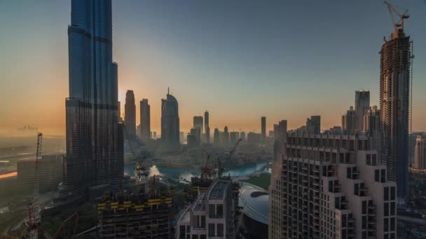 Panoramisch uitzicht op de skyline van Dubai centrum tijdens zonsopgang met een winkelcentrum, fonteinen en Burj Khalifa lucht ochtend timelapse — Stockvideo