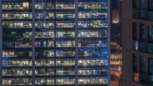 Bürogebäude außen am späten Abend mit eingeschaltetem Innenlicht und Menschen, die im Zeitraffer der Nacht arbeiten — Stockvideo