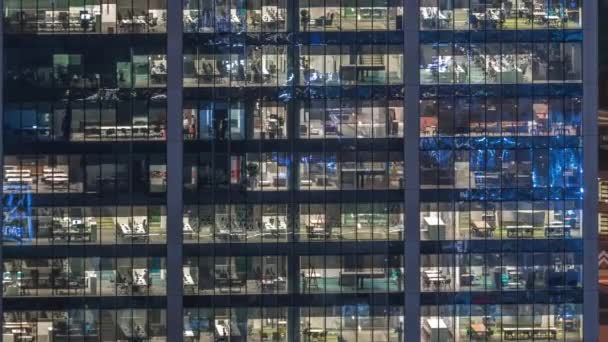 夜遅くに室内灯が点灯し、夜間のタイムラプスの中で働く人々がオフィスビルの外観 — ストック動画