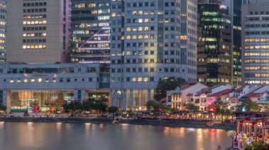 Singapur rıhtımında uzun gökdelenler var. Tekne rıhtımında merkez iş bölgesinde günden geceye doğru.