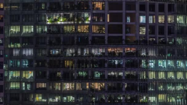 Moderní kancelářská budova s velkými okny v noci, v oknech svítí světlo — Stock video