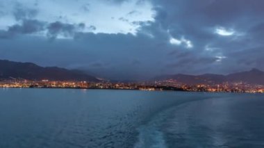 Dalgalı deniz manzarası ve açık denizde yelken açan gemiden liman manzarası.