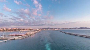 Dalgalı deniz manzarası ve açık denizde yelken açan gemiden liman manzarası.