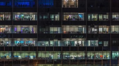 Modern ofis binası, gece vakti büyük pencereleri, pencereleri aydınlık.