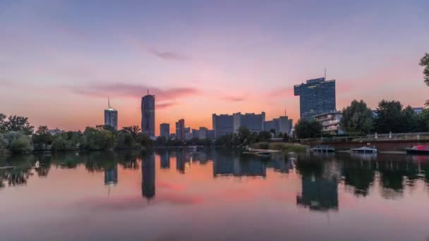 カイザーワッサー湖の反射を持つウィーン国際センターの高層ビル昼から夜のタイムラプス — ストック動画