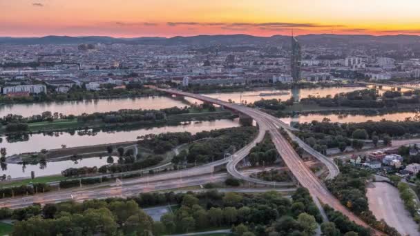 Panoramisch uitzicht vanuit de lucht over de stad Wenen met wolkenkrabbers, historische gebouwen en een boulevard langs de rivier van dag tot nacht in Oostenrijk. — Stockvideo