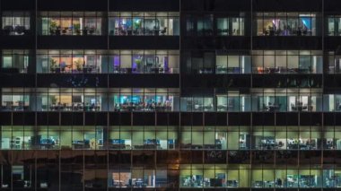 Modern ofis binası, gece vakti büyük pencereleri, pencereleri aydınlık.
