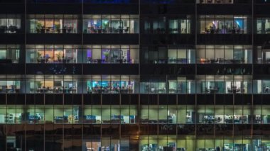 Modern ofis binası, gece vakti büyük pencereleri, pencereleri aydınlık.
