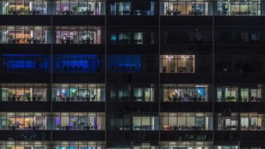 Modern ofis binası, gece vakti büyük pencereleri, pencereleri aydınlık.