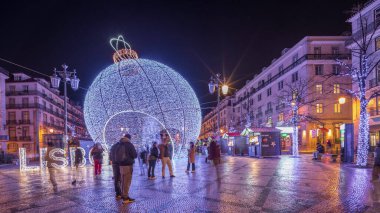 Panorama showing Christmas decorations with big ball on Luis De Camoes square (Praca Luis de Camoes) night timelapse. One of the biggest squares in Lisbon city in Portugal illuminated in the evening clipart
