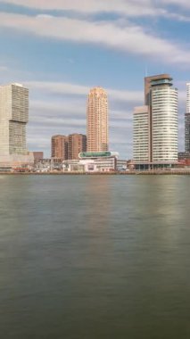 Panorama, Nieuwe Maas River bankasından Wilhelminapier ve Kop van Zuid 'e kadar olan zaman çizelgesini gösteriyor. Modern gökdelenler, gemi terminali ve Erasmus Köprüsü, kıyıdan geçen tekneler.