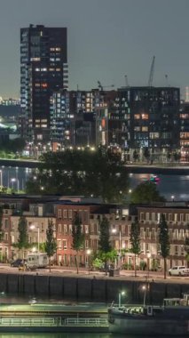 Geceleri Katendrecht yarımadasının panoramik zaman çizelgesi, Hollanda Rotterdam 'daki Maashaven limanı ve nehri. Aydınlatılmış şehir silüeti, modern gökdelenler ve geleneksel rıhtım evleri