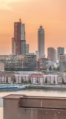 Günbatımında Rotterdam şehir merkezindeki modern binaların hava zaman çizelgesi, Hollanda. Finans bölgesinde kuleler ve gökdelenler, turuncu gökyüzü ile eski fabrika canlı bir ufuk çizgisi oluşturur