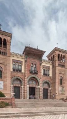 Maria Luisa Park 'taki Sevilla Sanat ve Gelenekler Müzesi cephesi. Plaza de America 'da Mudejar tarzı bir bina var. Bulutlu gökyüzü altında zaman atlaması. Sevilla, İspanya.