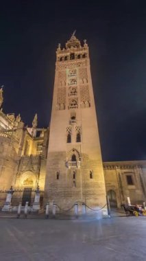 La Giralda ve Seville Katedrali geceleri aşırı hızlanarak altın ışıklarla parıldıyor. Tarihi çan kulesi, gotik detaylar ve aydınlatılmış sokaklar Sevilla, İspanya 'da büyülü bir atmosfer yaratıyor.