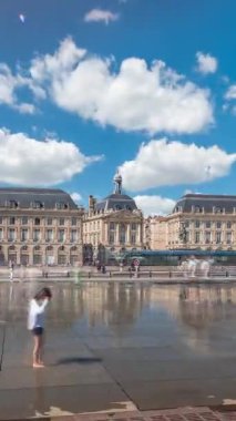 Place de la Bourse hyperlapse in Bordeaux, France, reflecting historic architecture. Tourists enjoy the landmark and the fountain. Timelapse of traffic and tram passing by.