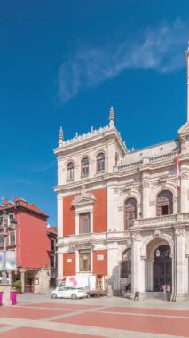 Panorama, Valladolid Plaza Belediye Başkanı Timelapse bayraklarıyla belediye binasının ön cephesini gösteriyor. Mavi gökyüzü ve şehrin göbeğindeki tarihi mimari. Yayalar bu merkez meydandan geçiyor..