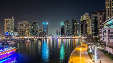 Dubai Limanı 'ndaki köprüden gece görüşü yanıp sönen ışıklarla aydınlanan kuleler yüzen yatlar ve botlarla suya yansıyordu Birleşik Arap Emirlikleri. Dubai bölgesi ve yapay bir kanal.