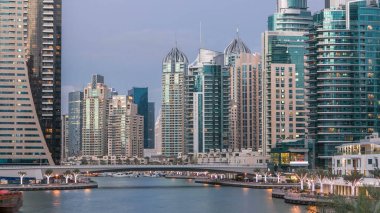 Dubai Marina rıhtımı, Dubai 'deki köprüden gece vardiyasına kadar uzanan kuleleri ve yatları olan Birleşik Arap Emirlikleri. Çevresinde yapay kanallar ve aydınlık gökdelenler olan bir bölge.