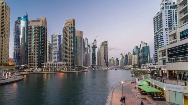 Dubai Marina rıhtımı, Dubai 'deki köprüden gece vardiyasına kadar uzanan kuleleri ve yatları olan Birleşik Arap Emirlikleri. Yapay kanalları ve gökdelenleri olan bir bölge.