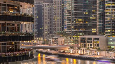 Dubai Marina rıhtımı kuleleri ve Dubai 'deki alışveriş merkezinin balkonundan restoranlara yakın köprüsü olan Birleşik Arap Emirlikleri hava geçiş zamanı..
