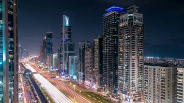 Dubai Kuleleri 'nin şehir merkezinden gece gündüz geçiş zamanı. Gün batımından sonra Şeyh Zayed 'in gökdelenli hava manzarası. Yollarda ve metro hattında trafik vardı. Güzel bulutlu gökyüzü