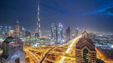 Modern gökdelenler ve yoğun gece otoyolları Dubai şehir merkezindeki lüks geçiş zamanlarında. Kule çatısından üst hava manzarası. Yol kavşağı trafiği. Dubai, Birleşik Arap Emirlikleri