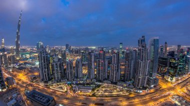 Dubai 'nin panoramik silueti günden geceye, Birleşik Arap Emirlikleri. Ünlü gökdelenler kule çatısı manzaralı. Güzel bulutlu gökyüzü. Renkli seyahat ve iş geçmişi