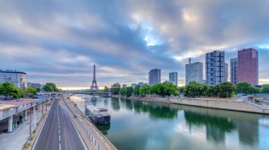 Eyfel Kulesi Seine Nehri 'nde ve Fransa' nın Paris şehrinde teknelerle renkli gündoğumu zamanı. Grenelle Köprüsü 'nden hava görüntüsü. Modern binalar ve yol trafiği. Dramatik bulutlar