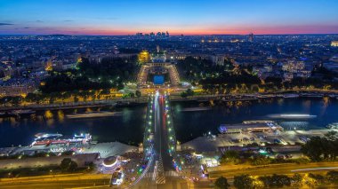 Paris, Fransa 'daki Eyfel Kulesi' nden Palais de Chaillot ile Trocadero 'ya gündüz ve gece geçiş zamanı üzerinde hava manzarası. Seine nehri ve gemisinin geçtiği gözlem güvertesinin üst görüntüsü.
